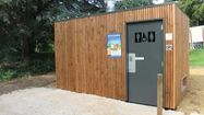 Une vue extérieure des toilettes écologiques, une cabane en bois avec panneau explicatif au parc du Couloumé à Auch